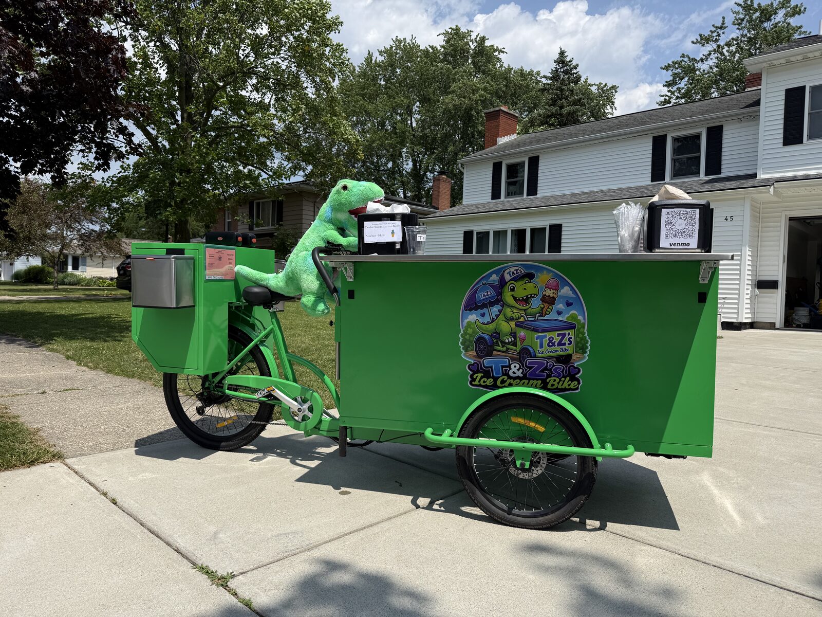 T&Z's Ice Cream Bike parked in a neighborhood driveway with the plush dinosaur mascot riding along
